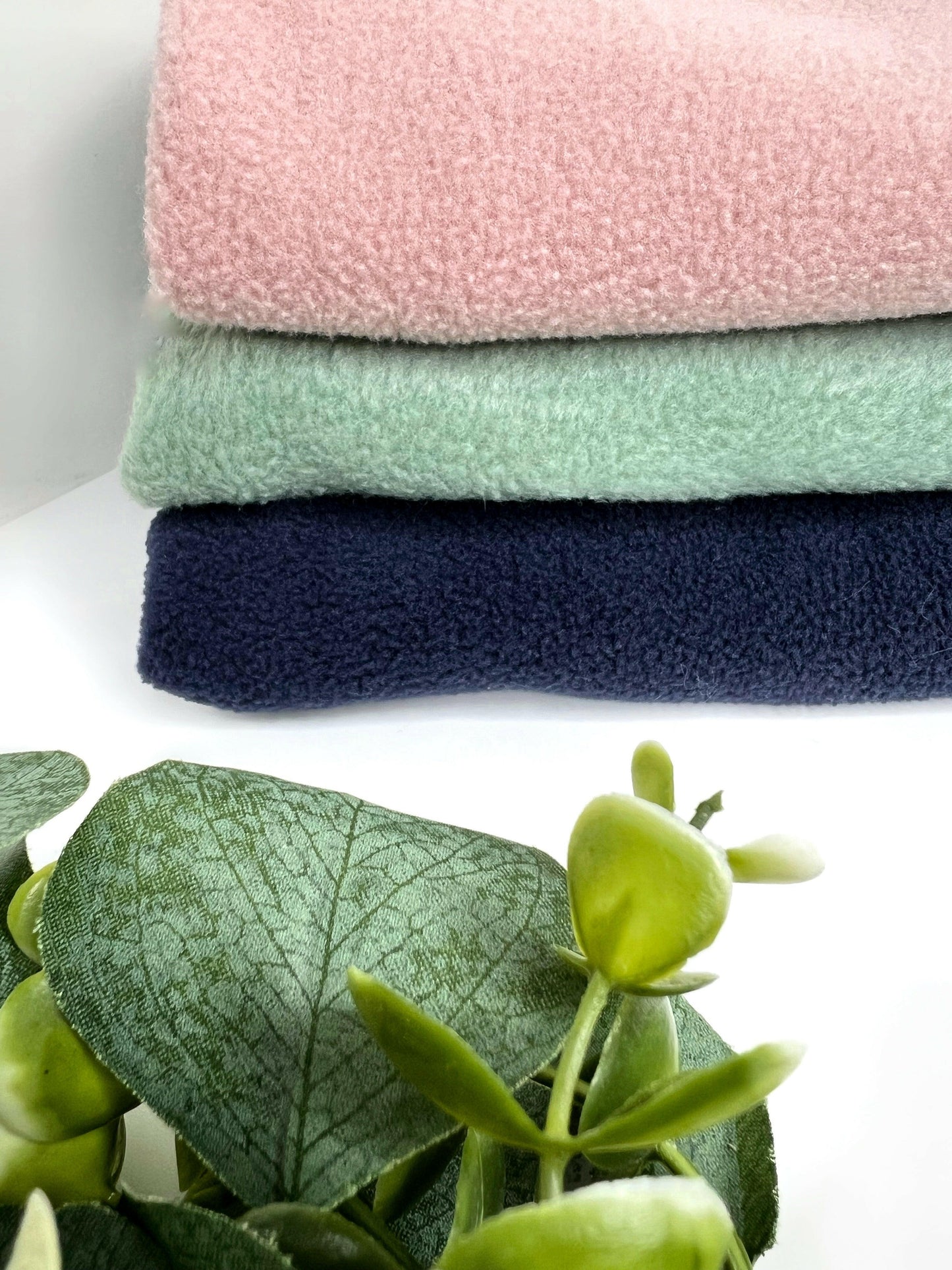 Navy, sage and peach fleeces in a pile