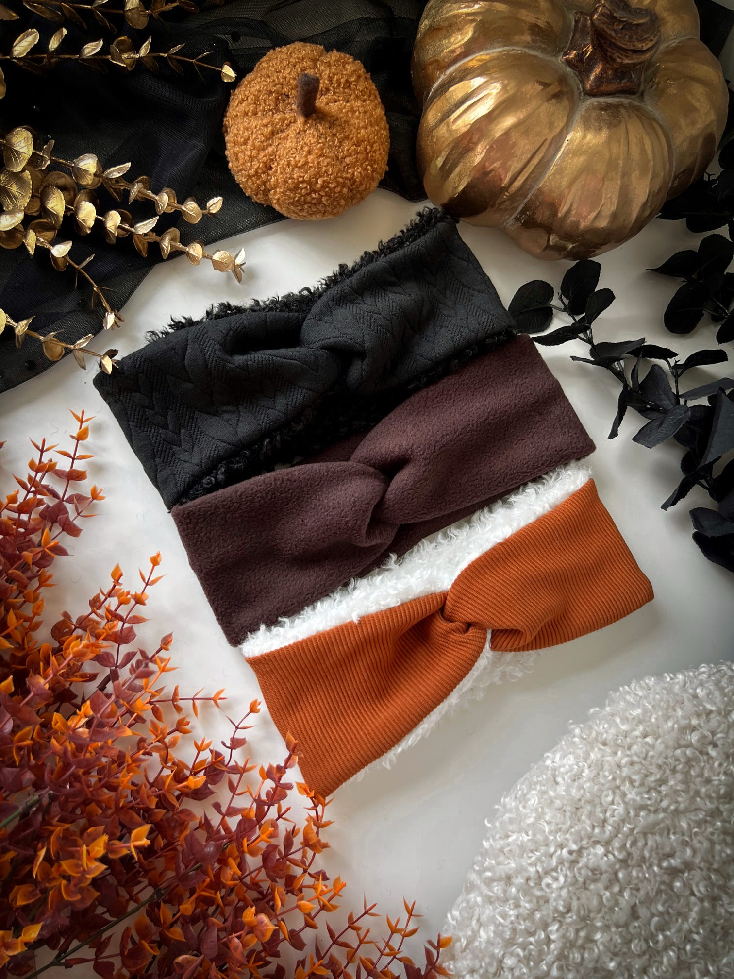 Set of three headbands in black, brown, and orange on a textured surface with decorative elements.