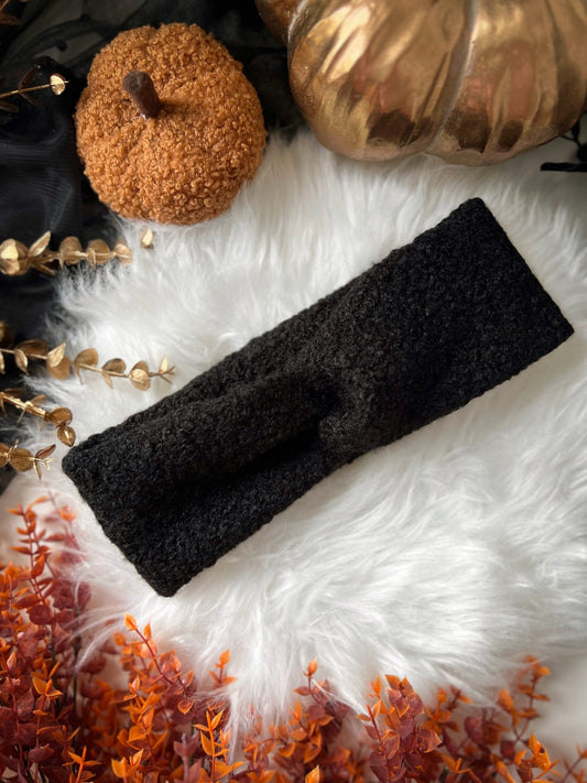 Black headband on a white fur surface with decorative pumpkins and gold leaves.