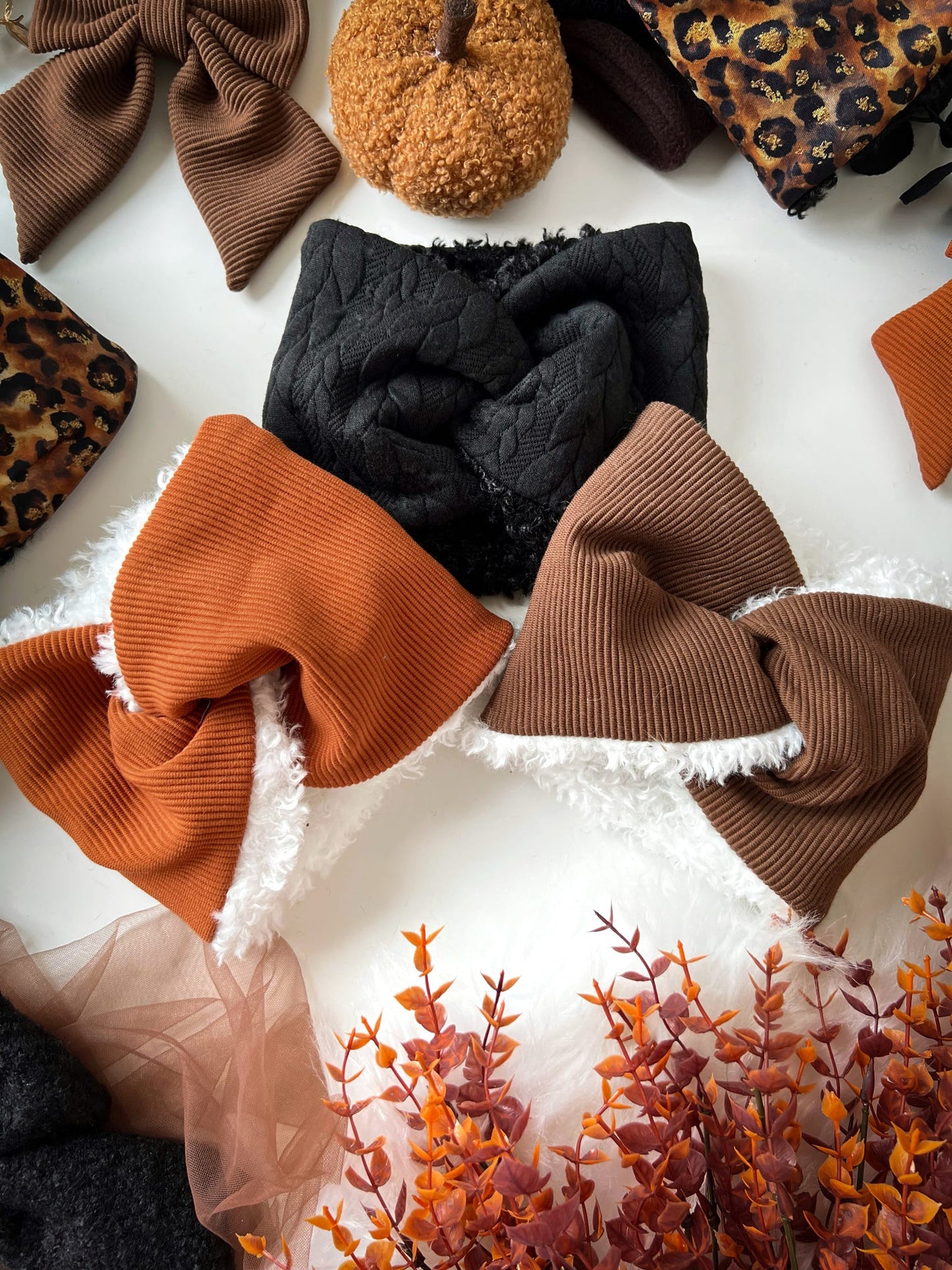 Collection of autumn-themed dog accessories including bows and dog snoods on a white background.